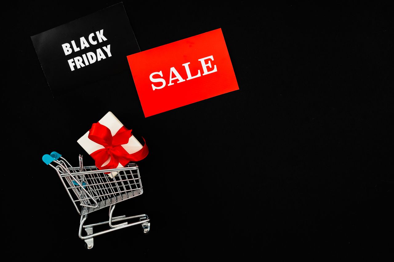 why-choose-us-03 Shopping cart with gift box and Black Friday Sale signs on black background. Perfect for holiday promotions.