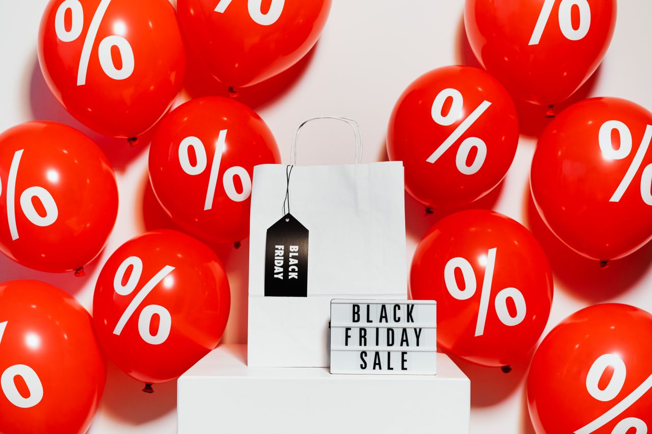 why-choose-us-03 Vibrant Black Friday sale display with red balloons and a shopping bag showcasing discounts.