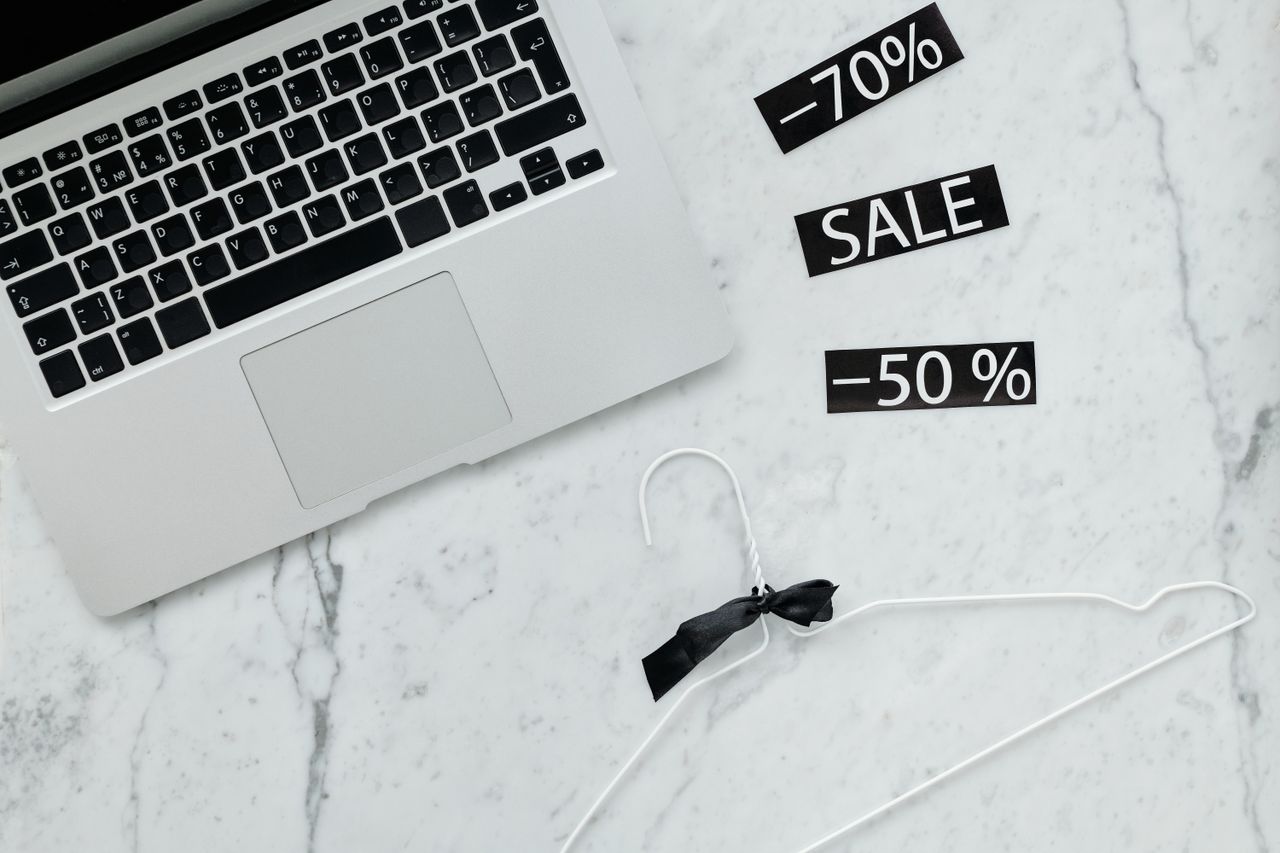about-02 Flat lay of a laptop, hanger, and sale stickers on a marble desk, ideal for Black Friday themes.